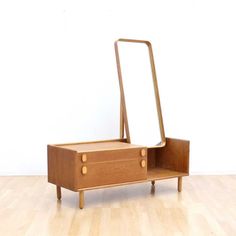 a small wooden dresser with a mirror on it's top and drawers underneath the drawer