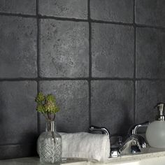 a white sink sitting under a bathroom faucet next to a gray tiled wall