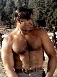 a shirtless man with no shirt standing in front of a fence and looking at the camera