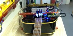 an electric guitar sitting on top of a wooden table next to some wires and other electronic equipment