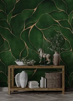 a table with vases and plants on it in front of a green wallpaper