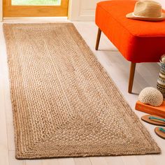 an orange bench sitting in front of a window next to a rug on the floor