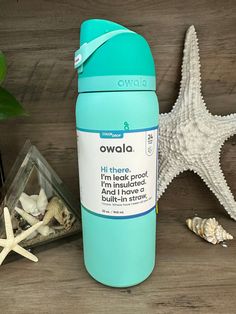 a blue water bottle sitting on top of a wooden table next to shells and starfish