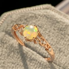 an opal and diamond ring sitting on top of a cloth