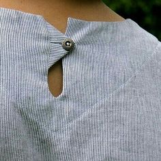 a close up of a person wearing a blue shirt with a button on the back