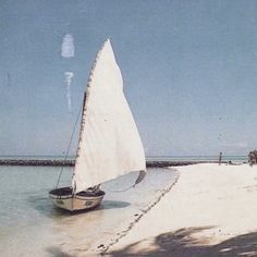 a sailboat on the beach with people in the background