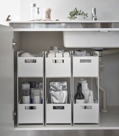 three white bins under a kitchen sink filled with toiletries and other bathroom items