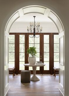 an archway leading into a dining room with chandelier and table in the center