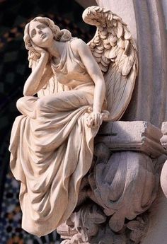 an angel statue sitting on the side of a building