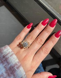 a woman's hand with red nail polish and a ring on her left hand