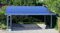 a metal structure with blue tarps on it in the middle of some bushes and trees