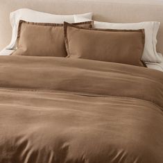 a bed with brown sheets and white pillows