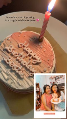 a birthday cake with a lit candle on it and a photo of two women in the background