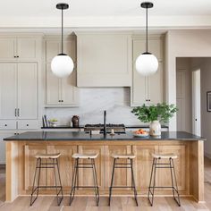 a kitchen with three stools and an island in front of the stove top oven