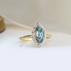 a close up of a ring with a blue stone in the center and diamond accents