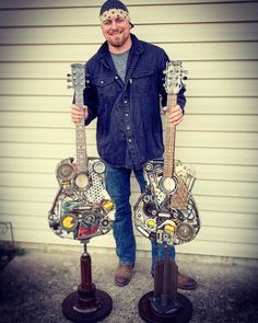 a man standing next to two guitars made out of junk