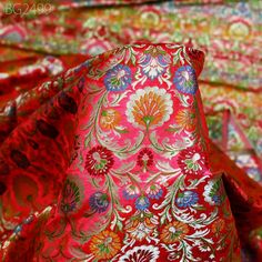 the fabric is red and has colorful flowers on it, as well as many other colors