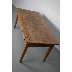 a small wooden table sitting on top of a gray floor next to a white wall