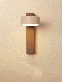 a wall light mounted on the side of a white wall with a brown wooden frame