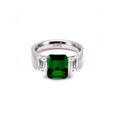 an emerald and diamond ring with three diamonds on the side, set in white gold