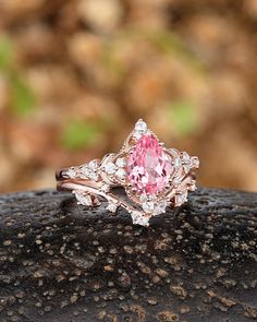 a pink diamond ring sitting on top of a rock