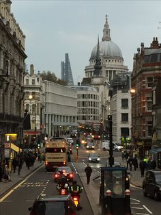 a city street filled with lots of traffic next to tall buildings on either side of the road