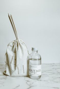 a white bag sitting next to a bottle with two sticks sticking out of it on top of a marble counter