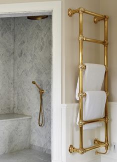 a gold towel rack in a bathroom with marble walls and floor, next to a shower