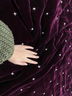 a woman's hand on top of a purple blanket with white stars in the middle