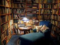 a blue chair sitting in front of a bookshelf filled with lots of books