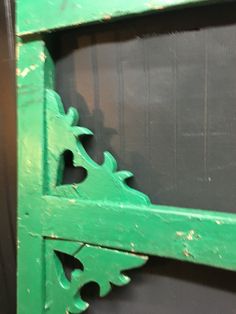 an old green wooden shelf with decorative carvings on it's sides and bottom, against a black background