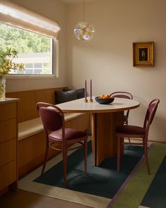 a dinning room table with two chairs and a bowl of fruit on the table