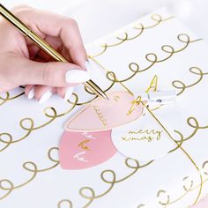 a person writing on a piece of paper with a gold pen in their left hand