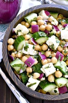 a wooden bowl filled with chickpeas and cucumber salad