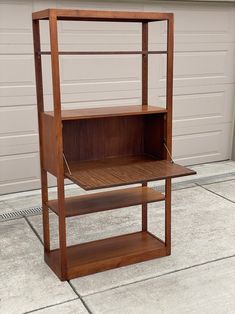 a wooden shelf sitting on top of a cement floor next to a garage door,