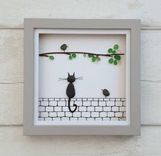 a cat sitting on top of a brick wall next to a tree branch with green leaves