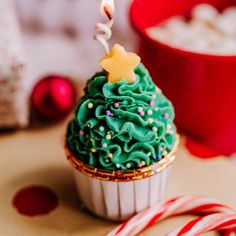 a cupcake with green frosting and a lit candle