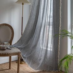 a room with a chair, lamp and curtain in the corner on top of it