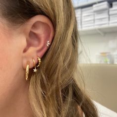 a close up of a person wearing earring with two stars on the front and one star on the back