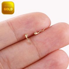 a tiny gold nose ring on someone's finger with the word gold written in it