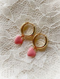 These adorably sweet huggie hoops have a charm of a small puff heart coated in shiny enamel. Huggie style hoop earrings are hinged at the bottom and click to clasp. Choose from pink or white. Gold plated. 7/8" long. Cute Huggie Jewelry For Valentine's Day, Cute Huggie Hoop Earrings For Valentine's Day, Pink Small Hoop Earrings In Cute Style, Cute Huggie Heart Earrings For Pierced Ears, Trendy Pink Huggie Earrings As Gift, Cute Small Hoop Pink Earrings, Cute Huggie Earrings With Heart Charm, Cute Dangle Hoop Earrings For Valentine's Day, Cute Huggie Hoop Earrings