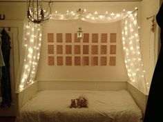 two teddy bears laying on a bed under a canopy with lights strung over the headboard