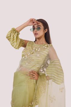 The stylish green organza saree with cold-shoulder balloon-sleeved blouse, embroidered with cut dana, off-white stripes blouse. Shop designer saris online in the USA from Pure Elegance. Disclaimer: The actual product may vary slightly from the image. These are custom orders, hence expect slight variation in color and placement of the motif or buta. ESTIMATED DELIVERYBecause this is a custom order, it would take about 4 weeks from the date of purchase. RETURN POLICYThis product is a custom order and cannot be returned or exchanged. Green Organza Saree, Stripes Blouse, Suits Indian, Sharara Suits, Fashion Journals, Pure Elegance, Balloon Sleeve Blouse, Traditional Fabric, Organza Saree