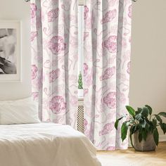 a white bed sitting next to a window covered in pink curtains