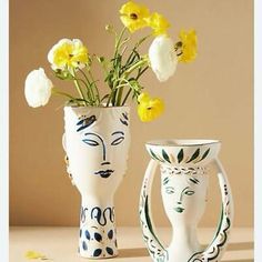 two white vases with yellow flowers in them