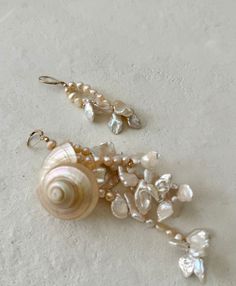 two seashells and pearls are hanging from earrings