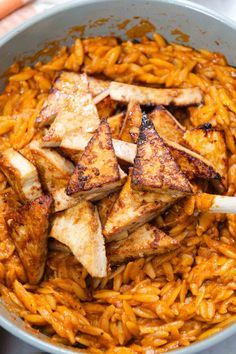 tofu and noodles in a pan with carrots on the side, ready to be eaten