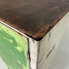 an old green and white cabinet with peeling paint on the top, against a white background