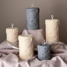 four candles with faces on them are sitting on a blanket and wrapped in a ribbon