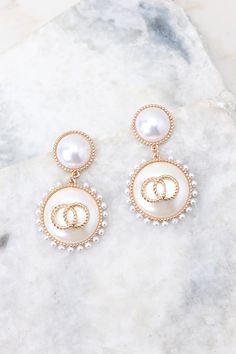 Look elegant and glamorous with these Graceful Glamour Pearl Earrings! These earrings put the “glam” in glamourous! Shine bright with these exquisite earrings and get ready to be the belle of the ball! These earrings feature pearl studs, gold detailing, small pearls circling larger pearl dangles, and a secure post backing. • Earrings measure 2" in length and 1" in width Feminine Pearl Earrings For Evening, Feminine Evening Pearl Earrings, Pearl Embellished Earrings For Party, Glamorous Party Earrings With Pearl Charm, Chic Pearl Drop Clip-on Earrings For Party, Chic Pearl White Earrings For Formal Occasions, Chic White Earrings With Pearl Chain, Chic Round Clip-on Earrings For Weddings, Glamorous Pearl Charm Drop Earrings